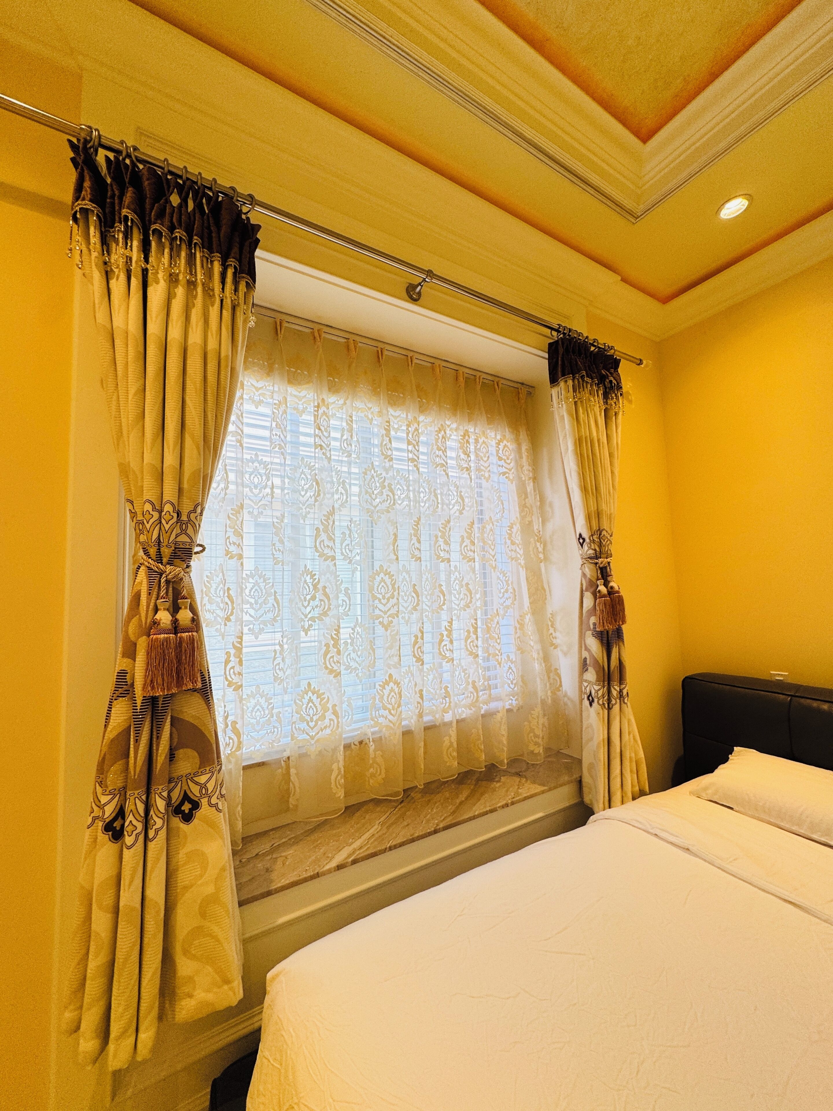 A hotel room with a bed, curtains, and a window with blinds.