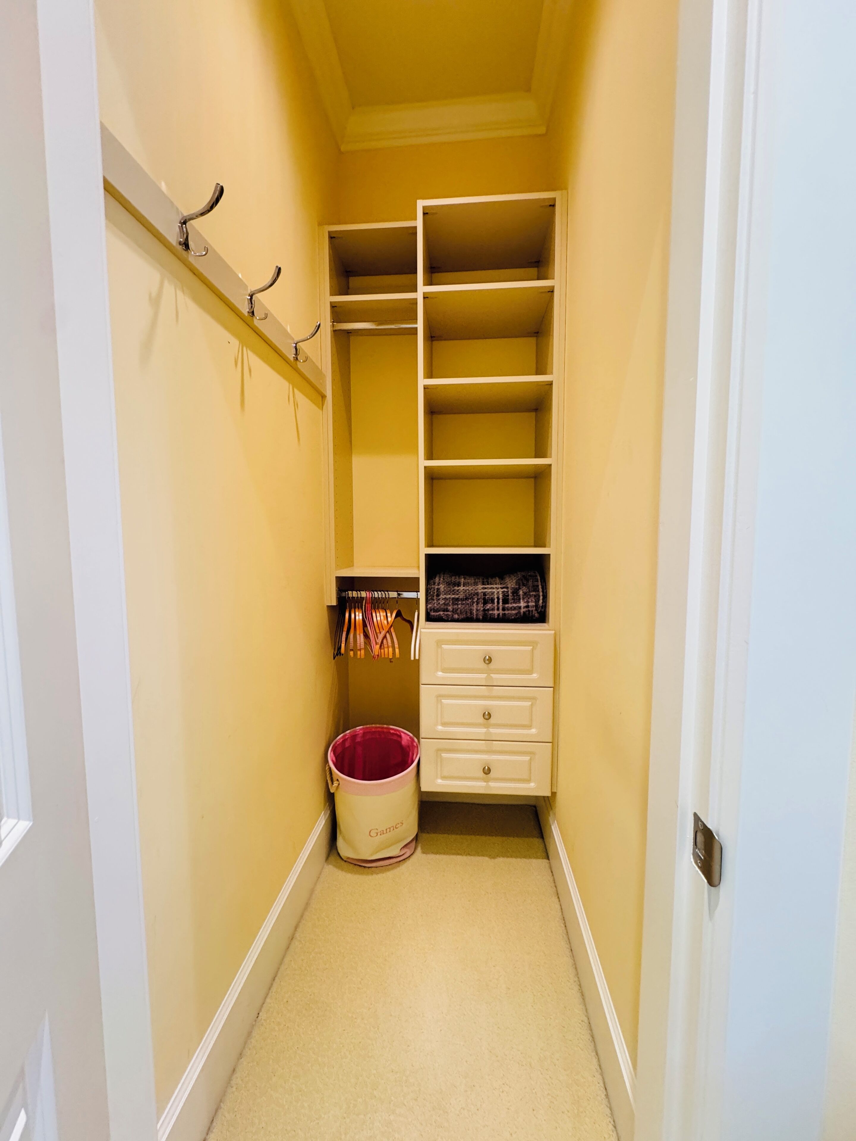 A narrow hallway with a closet containing shelves and hanging space.