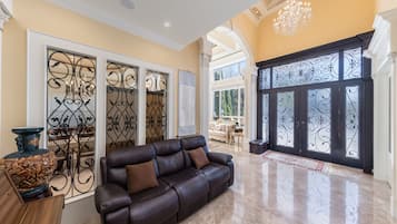 Un vaste espace de vie agrémenté d’un canapé en cuir, de grilles en fer décoratives et d’un lustre.