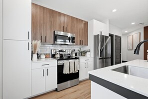 Una cocina moderna con armarios blancos, estufa de acero inoxidable, microondas y refrigerador.