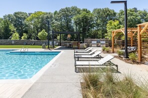 Una piscina con sillones de descanso y zona de barbacoa.