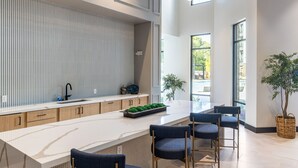 A modern kitchen with a marble countertop, wooden cabinets, and a built-in island with bar stools.