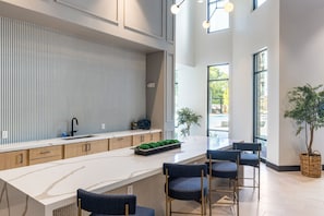 A modern kitchen with a marble countertop, wooden cabinets, and a built-in island with bar stools.