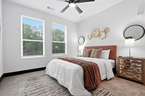 A bedroom with a bed, bedside tables, a ceiling fan, and a window with blinds.
