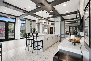 A modern kitchen with a central island, bar stools, pendant lighting, and a view of the outdoors.