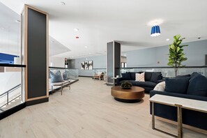 A modern hotel lobby with seating areas, a coffee table, and a plant.