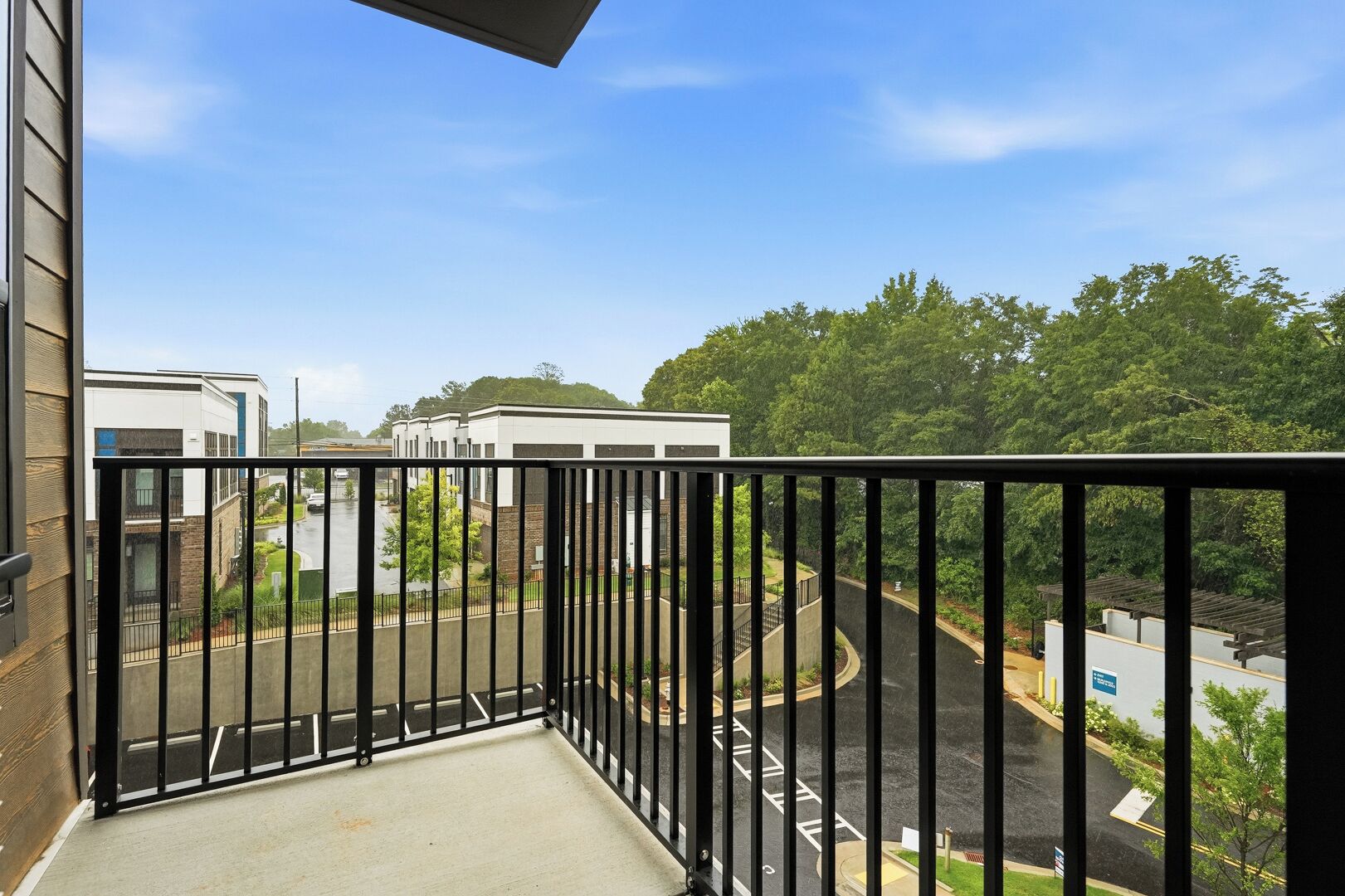 A balcony with a view of a parking area and buildings.