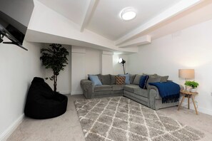 A living room with a sectional sofa, a bean bag chair, a patterned rug, a lamp, and a potted plant. - 6BR 6 Bath | Workspace | Family & Contractors (Darlington)