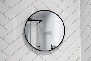 A round mirror with a reflection of a herringbone patterned wall and a door.