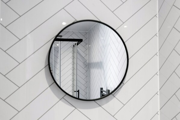 A round mirror with a reflection of a herringbone patterned wall and a door.