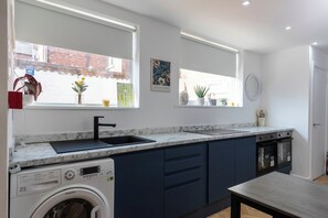 A modern kitchen with a built-in washing machine, a sink, and a window with a view of the street.