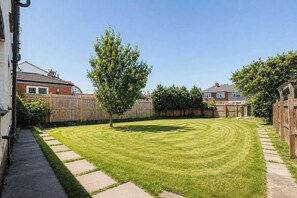 A well-maintained backyard with a lawn, a tree, and a wooden fence. - Durham 3BR -Parking free- Contractor friendly (Meadowfield)