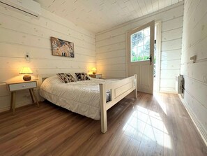 A bedroom with a bed, bedside lamps, a window, and a door. - Maison climatisée dans domaine avec piscine à Gassin (GASSIN)