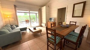 Un salon comprenant un canapé, une table basse, une table à manger avec des chaises, un téléviseur et une porte-fenêtre coulissante donnant sur un patio.