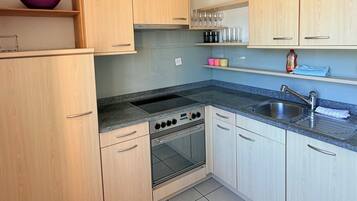 Eine Küche mit Holzausstattung, einem Herd, Backofen und Spüle.