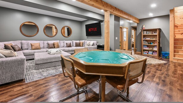 Un salon avec une table de billard, un canapé et une bibliothèque.