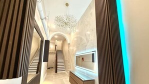 Ein moderner Flur mit Treppe, einer Holzkonsole und einem wandmontierten Spiegel.