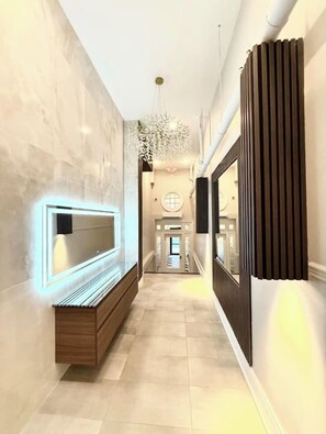 A hallway with a bench, a wall-mounted TV, a chandelier, and a door at the end. - High-End Center City 2 Bed & 2 Bath Apartment (Philadelphia)