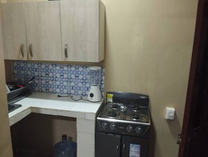 A kitchen with a stove, a blender, and a water dispenser.