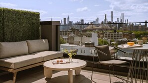 En takterrass med en soffa, ett bord och en stol, med utsikt över stadsbilden.