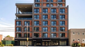 En byggnad med flera våningar och en modern arkitektonisk design, med en fasad som kombinerar tegel och glas, stora fönster och ett platt tak.