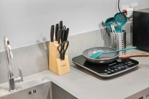 Eine Küche mit Arbeitsplatte, einer Pfanne auf einer Induktionskochplatte, einem Messerblock und einem Utensilienhalter.