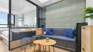 Un interno moderno con un divano, un piccolo tavolo rotondo, un angolo bar e vista tramite una parete divisoria in vetro.