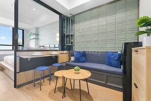 Ein modernes Interieur mit einer Couch, einem kleinen runden Tisch, einer Bar und Blick durch eine Glastrennwand.