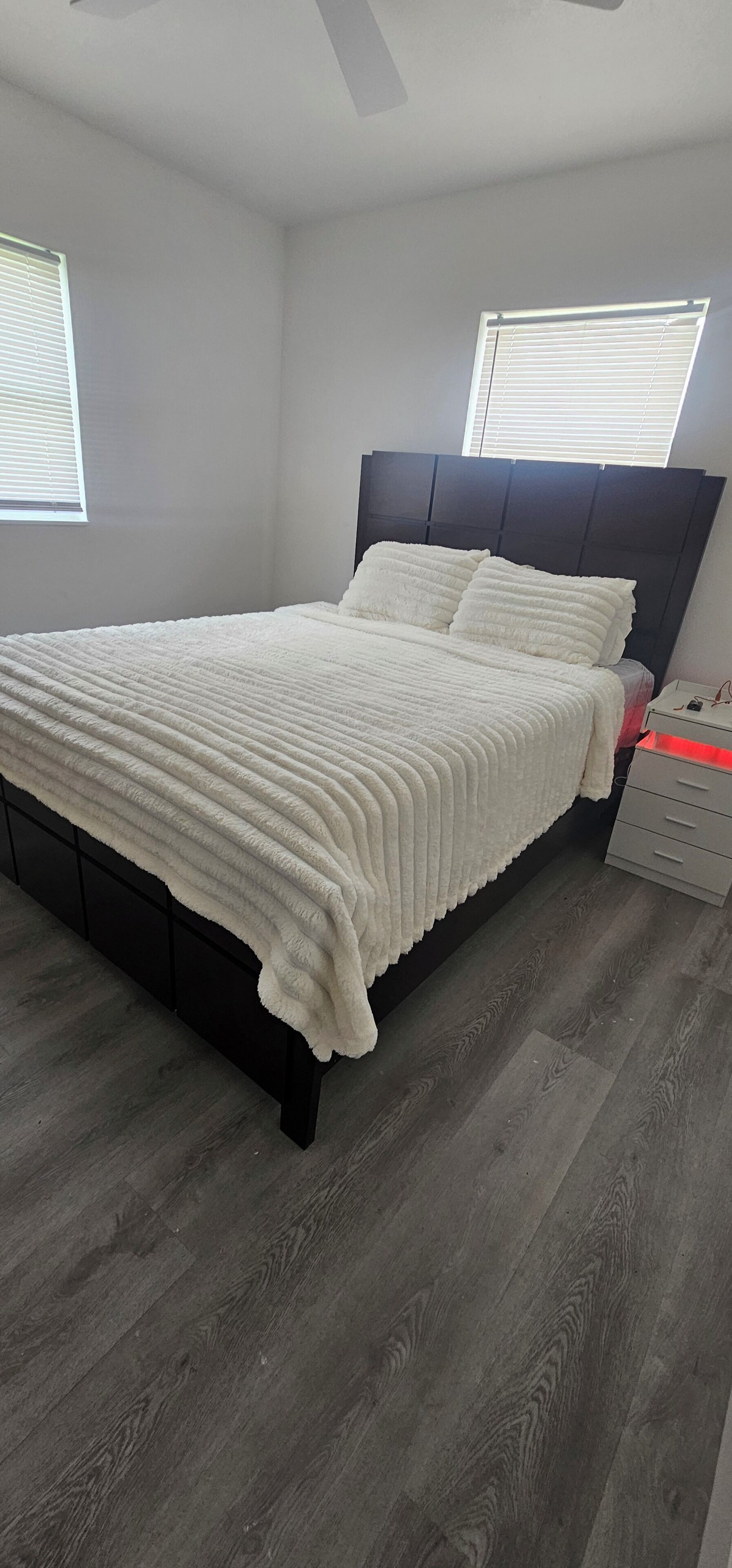 Um quarto com uma cama, uma mesa de cabeceira e uma janela com persianas.