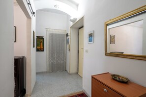 A hallway with a wooden cabinet, a mirror, and a door leading to another room. - La Casetta di Piazza Vittorio (Rome)