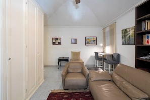 A living room with a sofa, a chair, a small table, and a bookshelf. - La Casetta di Piazza Vittorio (Rome)