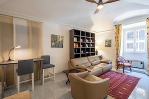 A living room with a sofa, two chairs, a coffee table, a bookshelf, and a radiator. - La Casetta di Piazza Vittorio (Rome)
