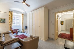 A living room with a sofa, a television, a wardrobe, and a red rug. - La Casetta di Piazza Vittorio (Rome)