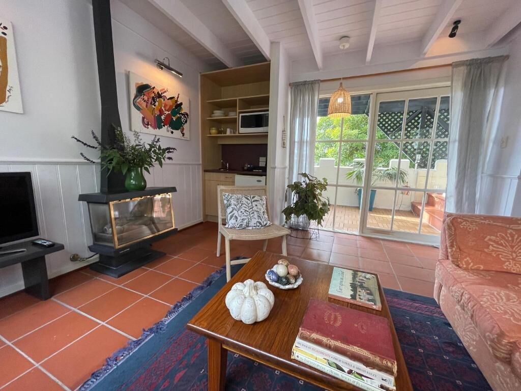 A living room with a fireplace, a television, a sofa, and a dining table with books and decorative items.