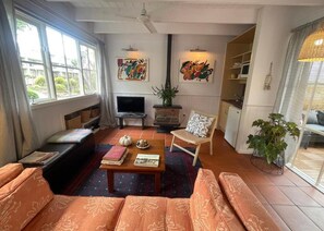 A living room with a sofa, a coffee table, a fireplace, a television, and artwork on the walls.