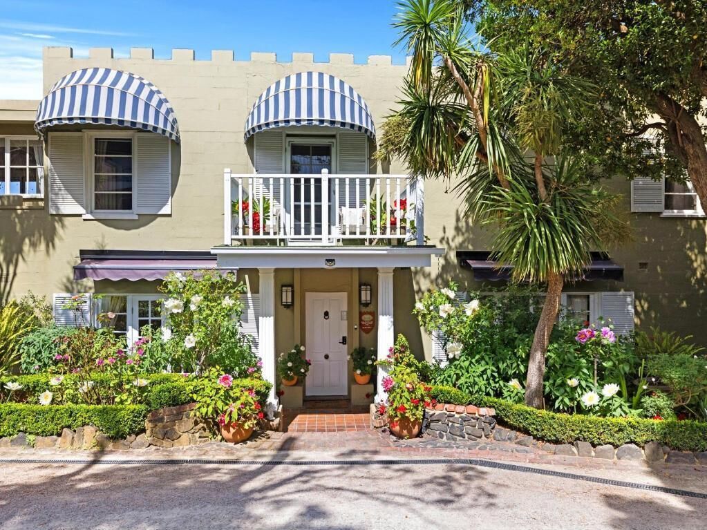 A two-story building with a balcony, a front door, and a small porch area.