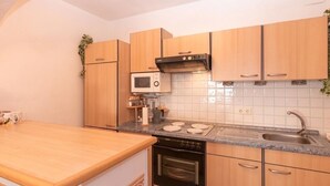 Una cocina con armarios de madera, un microondas, un horno, un lavamanos y una encimera.