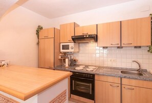 Eine Küche mit Holzausstattung, einer Mikrowelle, einem Backofen, einem Spülbecken und einer Arbeitsplatte.