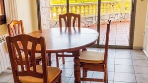 Comedor con una mesa redonda y sillas de madera, ventilador de techo y vistas a un paisaje montañoso a través de puertas de vidrio grandes.