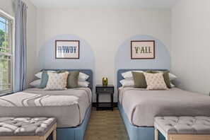 A bedroom with two beds, a nightstand, and framed wall art. - New 6BR Cabin with Hot Tub, Fire Pit, Indoor Pool - Game Table, Shuffleboard (Hollister)