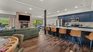 Una cucina moderna con mobili blu scuro, un frigorifero in acciaio inox e un televisore a schermo piatto montato sopra il piano di lavoro.