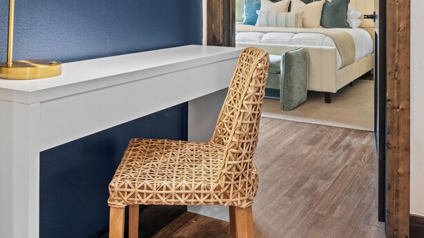 Una stanza con una scrivania, una sedia, un letto e una ventola a soffitto.