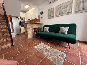 A kitchen with a stone island, a green sofa, and a tiled floor. - Estepona Old Town! 3bed house 5min Walk to Beach (Estepona)