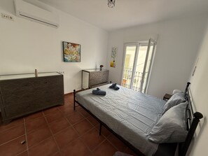 Een slaapkamer met een bed, een dressoir en een balkon met uitzicht.