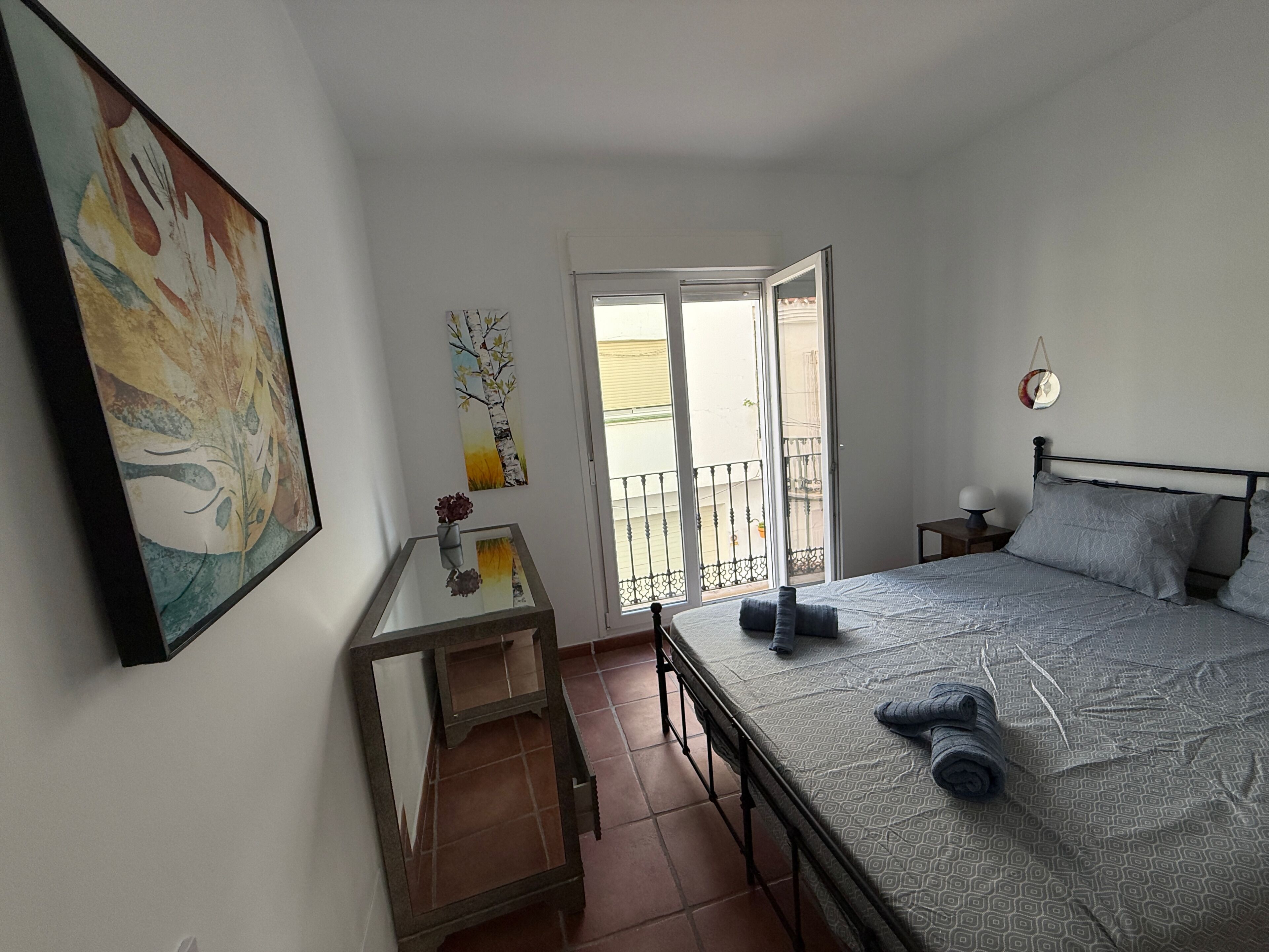 Une chambre à coucher avec un lit, un bureau, une chaise, une fenêtre et un balcon.