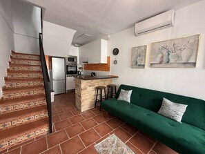 A kitchen with a central island, a green sofa, and a staircase with patterned tiles. - Estepona Old Town! 3bed house 5min Walk to Beach (Estepona)