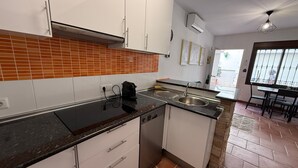 Una cucina moderna con mobili bianchi, un piano di lavoro nero e una parete di fondo rivestita di piastrelle.