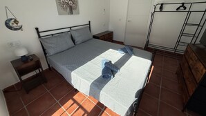 Una camera da letto con un letto, un comodino, una lampada, un elemento decorativo a parete, un armadio e una porta.