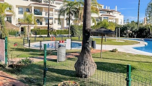 Et resort med swimmingpool, palmer og et afspærret område med en livreddersstol.