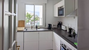 Et moderne køkken med hvide skabe, en sort bordplade, et vindue med udsigt og en indbygget mikrobølgeovn.